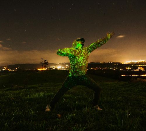 Silhouette of a person in a powerful pose against a green field.